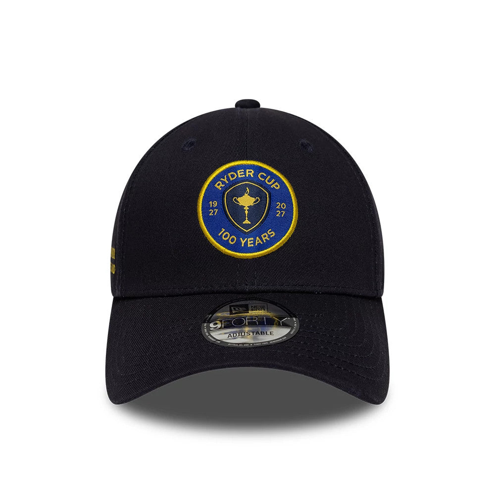 Ryder Cup 2027 100 Years Navy New Era 9FORTY Adjustable Cap, front view showing a yellow embroidered Ryder Cup logo with the years 1927 and 2027 on the front panel, a curved navy visor, and a 9FORTY size sticker on the visor.