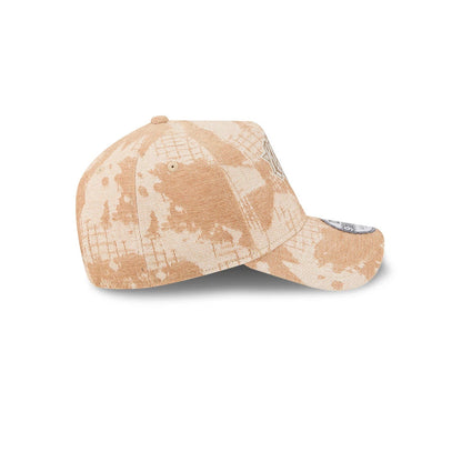 New York Knicks NBA Fall Story Beige New Era 9FORTY A-Frame Adjustable Cap, side view showing the beige structured crown with a unique camo pattern, a white embroidered side logo, and a curved visor with a 9FORTY size sticker.