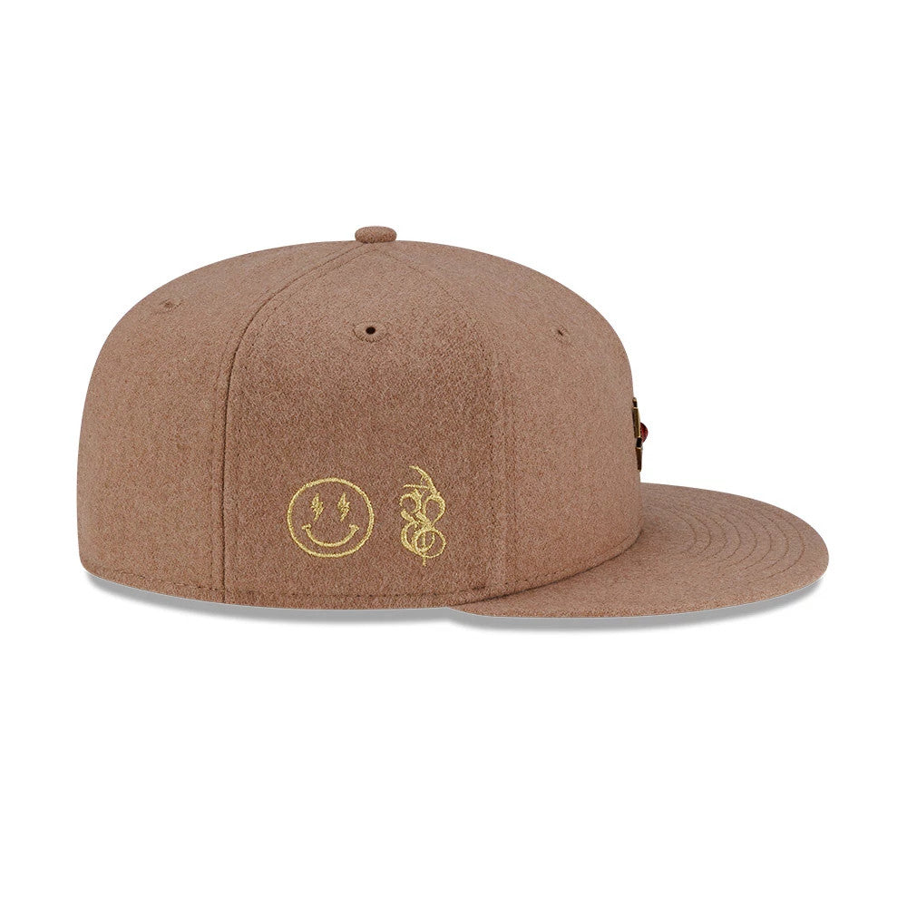 New Era X Omerta Balvin Beige New Era 59FIFTY Fitted Cap, side view showing the embroidered yellow smiley face and abstract line design on the left panel, with a structured beige wool crown and matching flat visor.