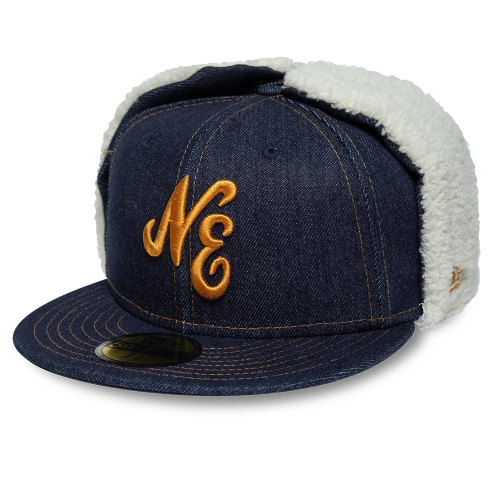 New Era Denim Navy Dogear 59FIFTY Fitted Cap, three-quarter view showing a gold embroidered NE logo on the front panel, navy denim fabric with white fleece-lined ear flaps, and a flat denim visor with a gold 59FIFTY size sticker.