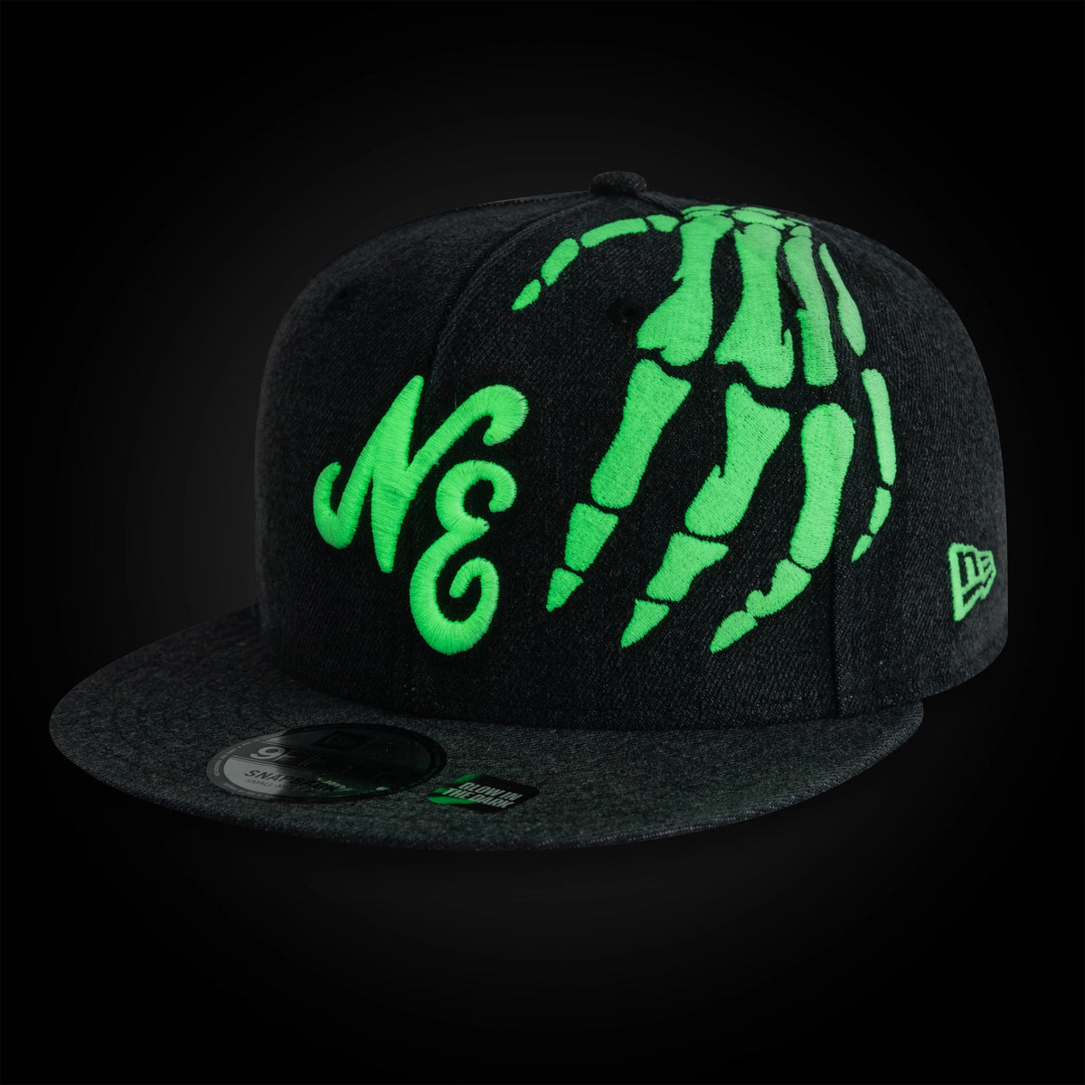 New Era Halloween Glow In The Dark Hands Black New Era 9FIFTY Snapback Adjustable Cap, three-quarter view showing green skeleton hand embroidery and NE text on the structured black crown, with a grey flat visor featuring a 9FIFTY size sticker.