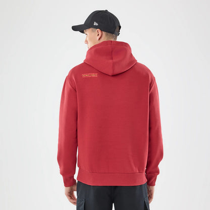 The model is wearing this Carlos Sainz Team Fifty5 Madrid Oversized Pullover Hoodie in dark red. 2