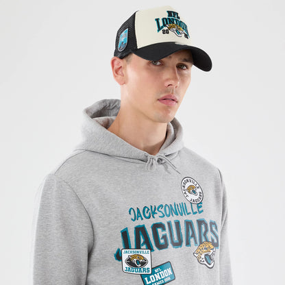New Era Jacksonville Jaguars NFL Patch Grey Pullover Hoodie, front view on-model showcasing the embroidered Jacksonville Jaguars lettering in teal across the chest, with various embroidered patches including the team logo and NFL London on the front.