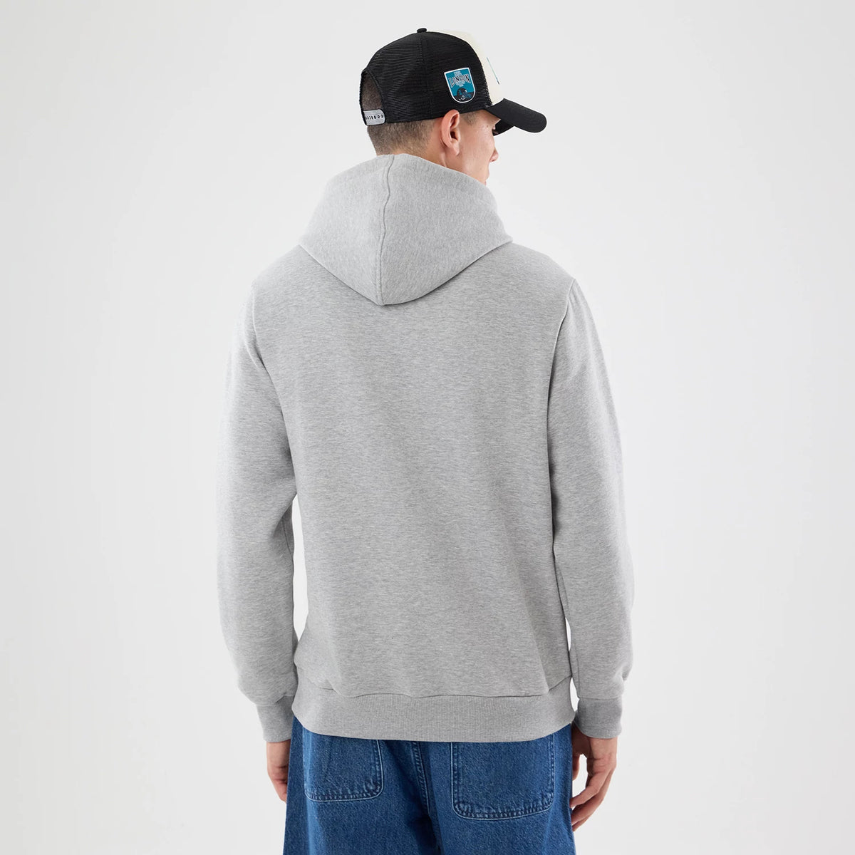 New Era Jacksonville Jaguars NFL Patch Grey Pullover Hoodie, back view on a model styled with blue jeans and a black cap, showing the simple grey design of the hoodie with a relaxed fit and the hood resting naturally on the back.