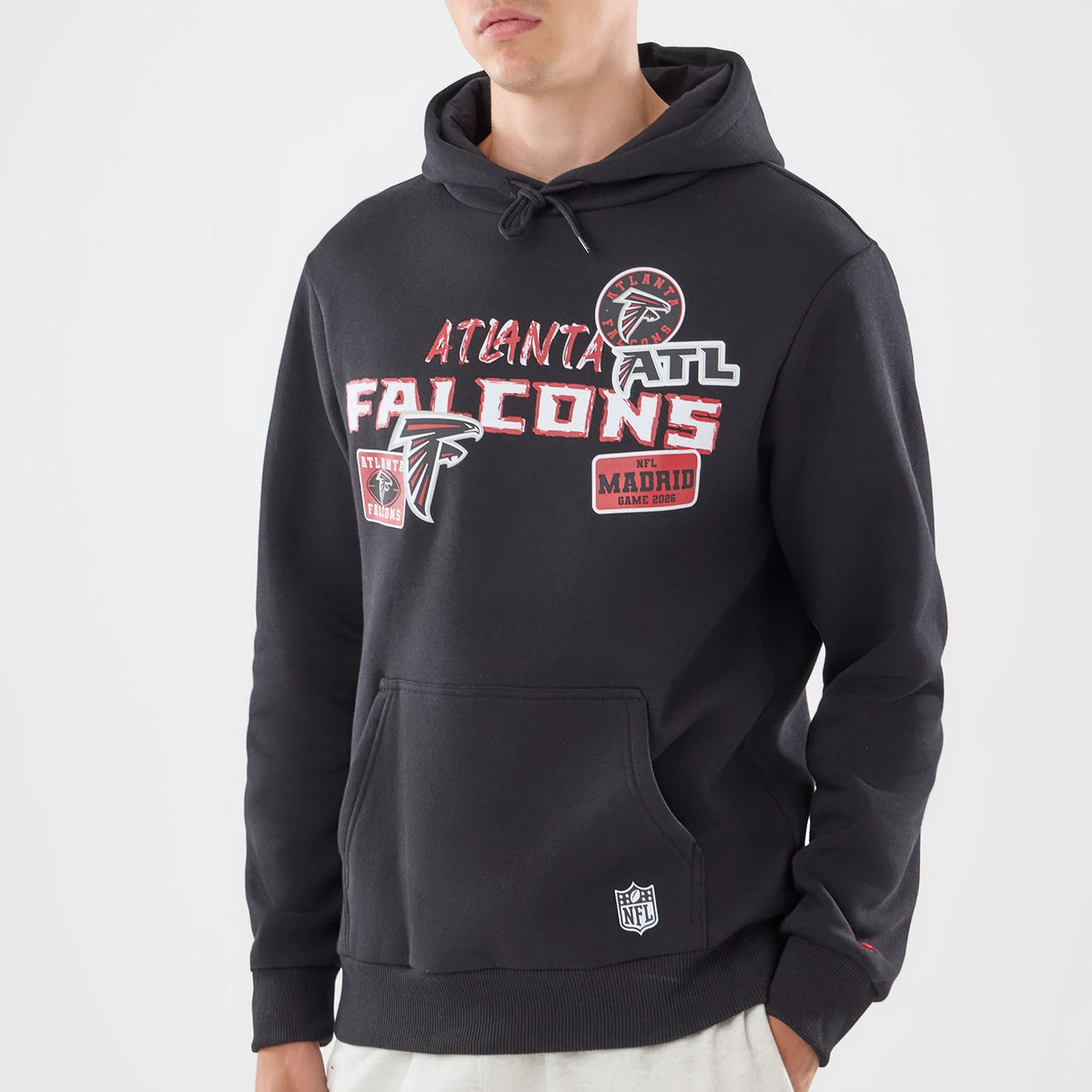 New Era Atlanta Falcons NFL Patch Black Pullover Hoodie, front view on-model featuring various embroidered patches, including the Atlanta Falcons logo and team name across the chest, a kangaroo pocket, and an NFL logo patch near the hem.