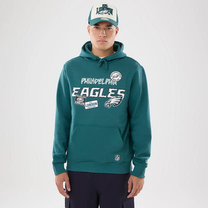 The model is wearing this NFL International Games 2026 Philadelphia Eagles Pullover Hoodie in dark green. 1