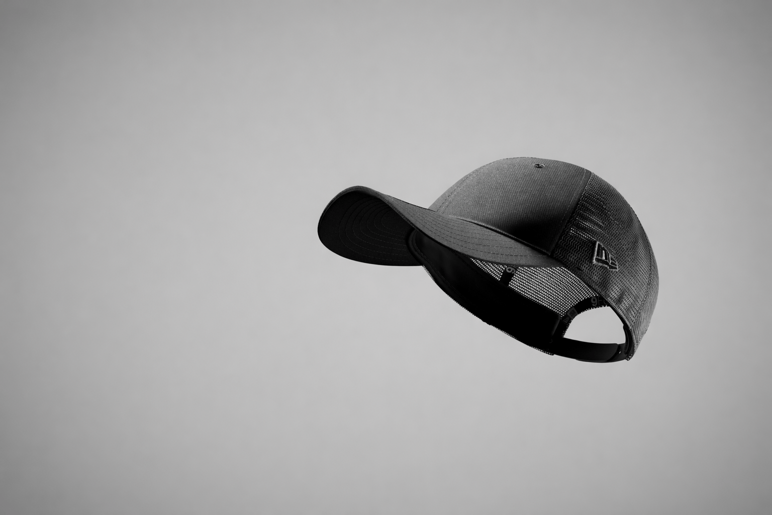 Black new era trucker cap on a grey background