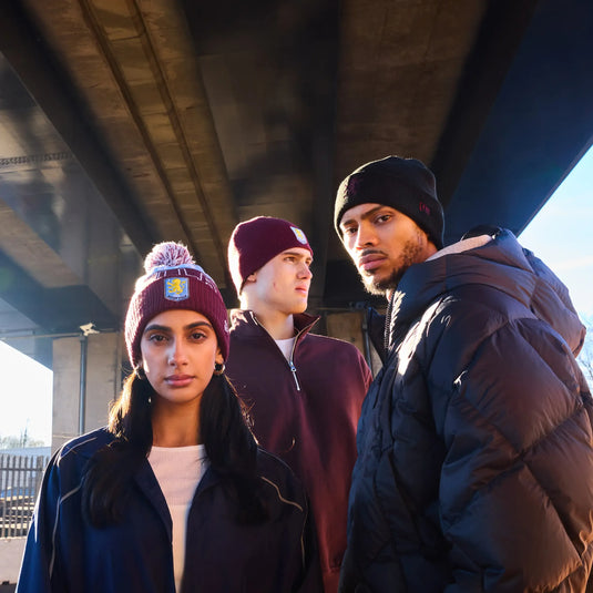 Three people standing under a bridge wearing winter clothing.
