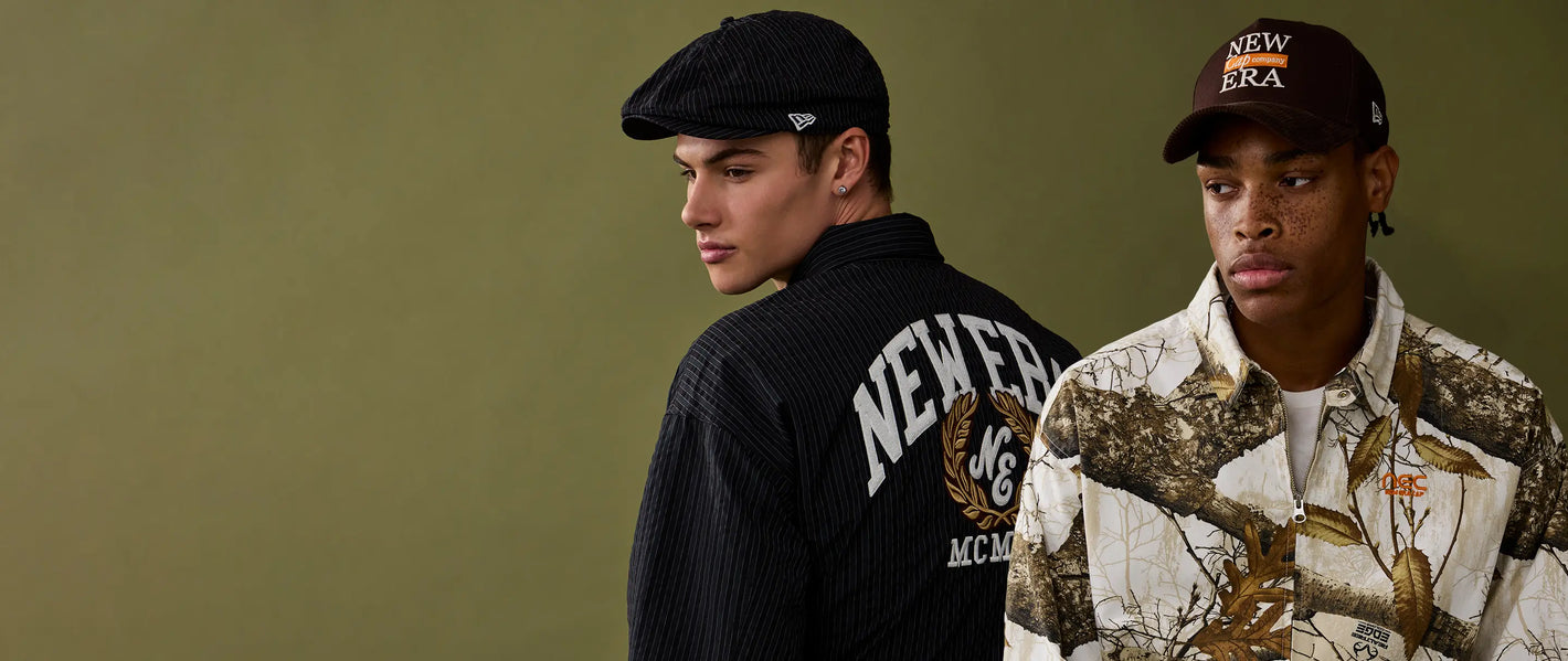 Two men wearing hats and jackets with visible branding against a plain background