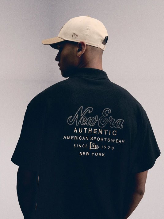 Person wearing a black New Era shirt with branding on a gray background