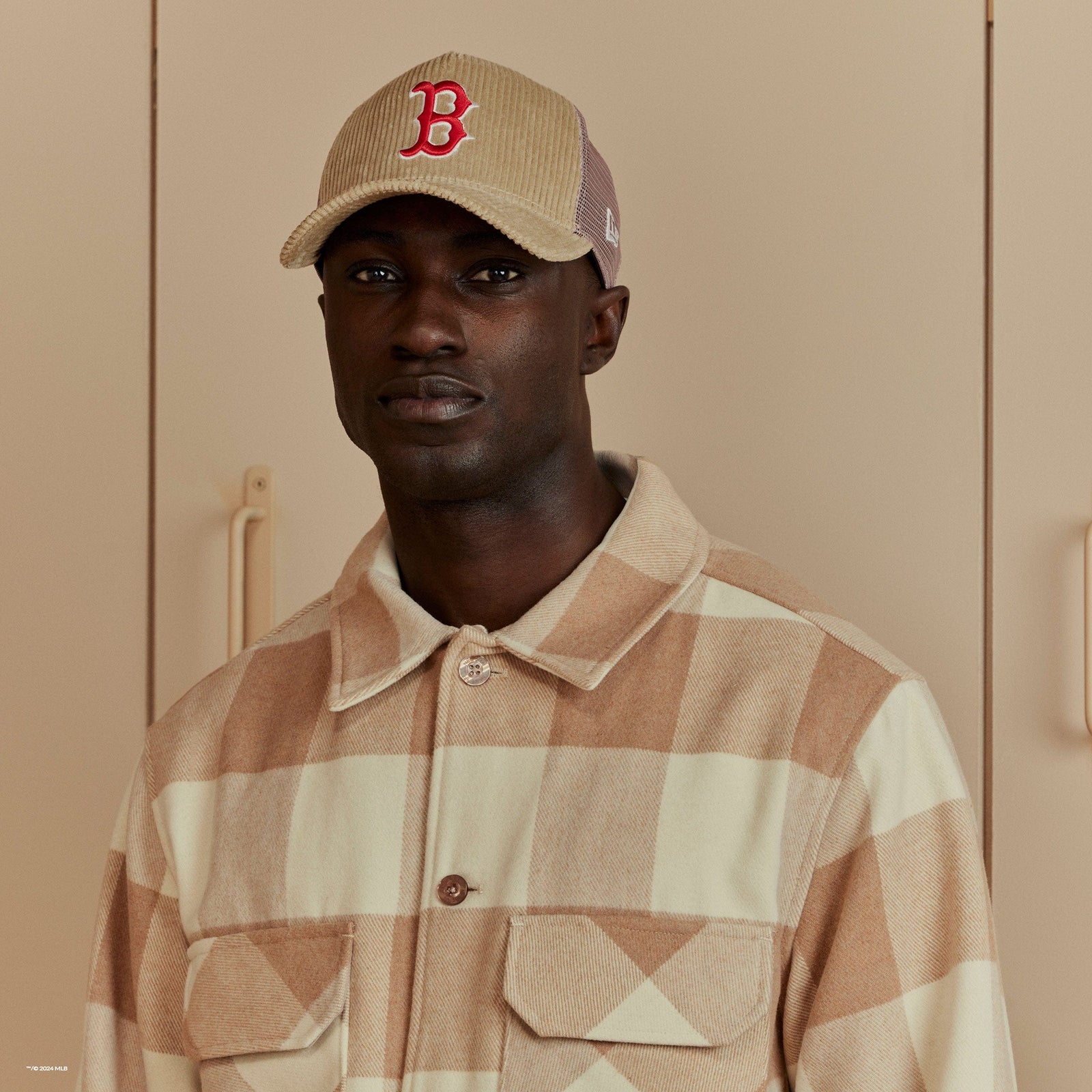 man wearing a plaid beige shacket with a beige cap