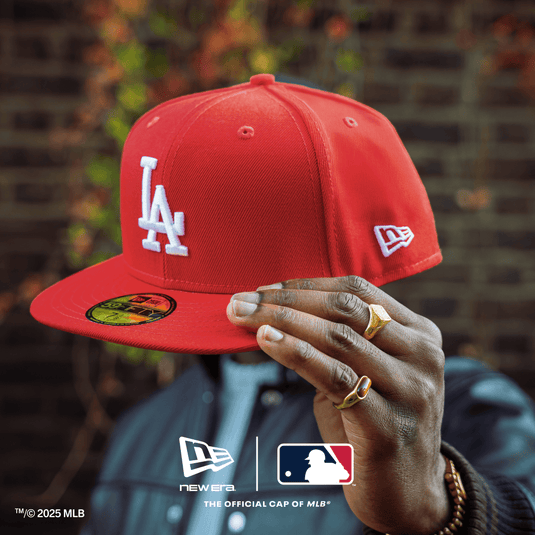 Red baseball cap with 'LA' logo held by a hand against a blurred background