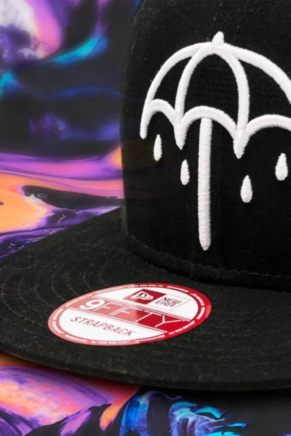 Black 9FIFTY New Era cap with white umbrella design on a colorful abstract background