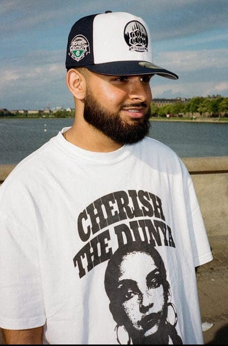 Man wearing a cap and t-shirt with a graphic design by a waterfront