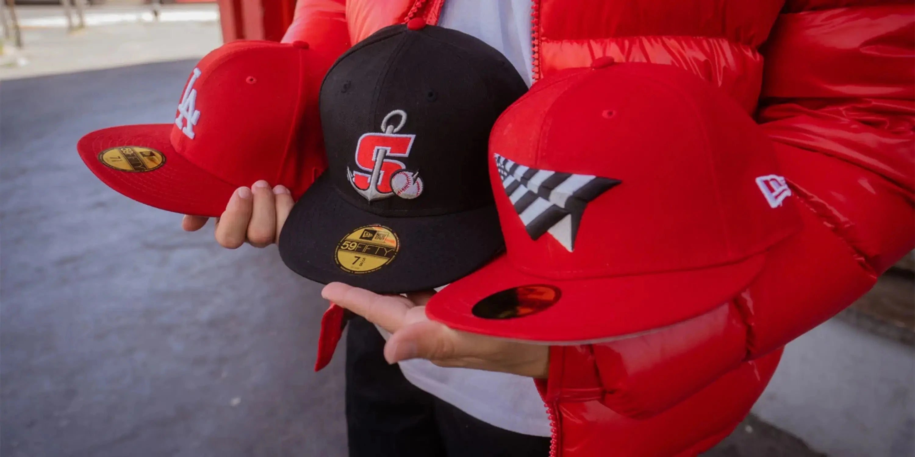 sgamo holding three new era caps in red and black