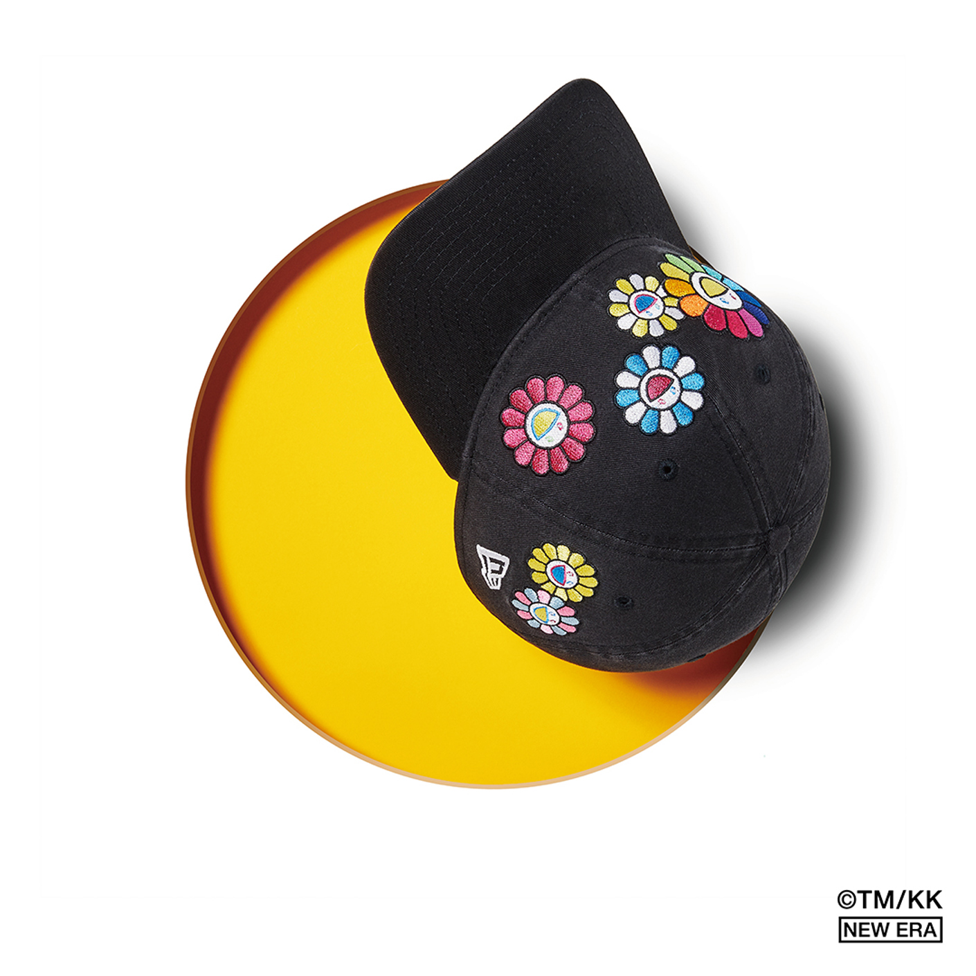 Fleur Takashi Murakami x casquette New Era devant fond jaune