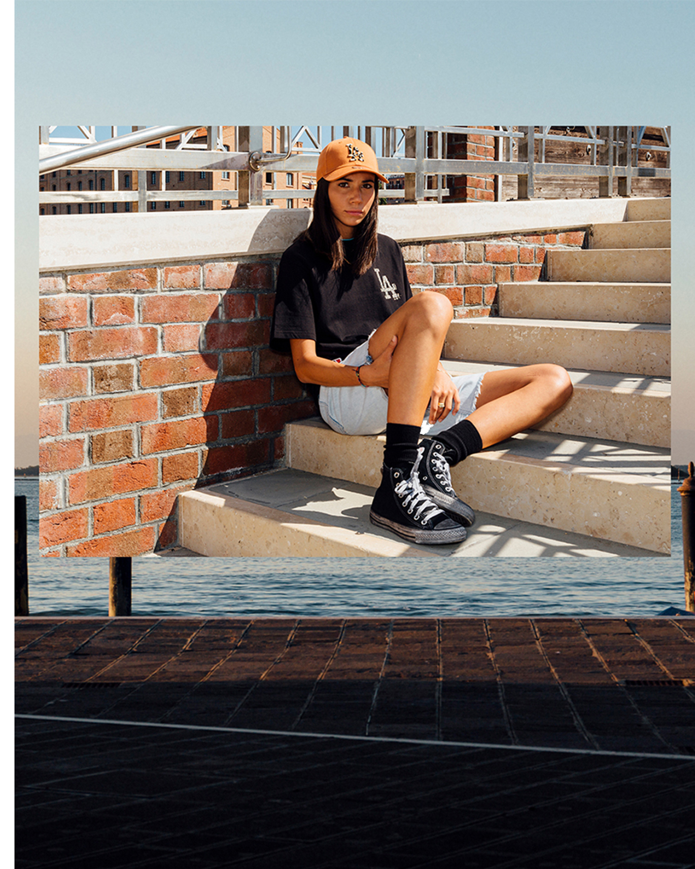 Girl sitting on steps wearing New Era LA Dodgers baseball cap and t-shirt