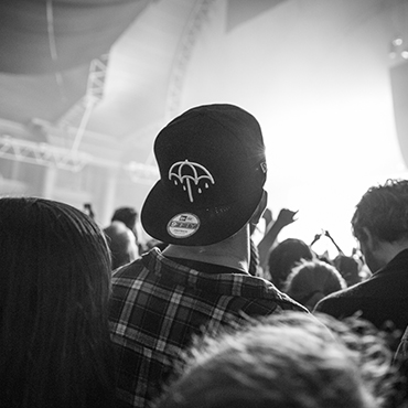 black and white image of man wearing a hat in a concert crowd